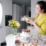 smiling vlogger showing delicious cakes while filming video